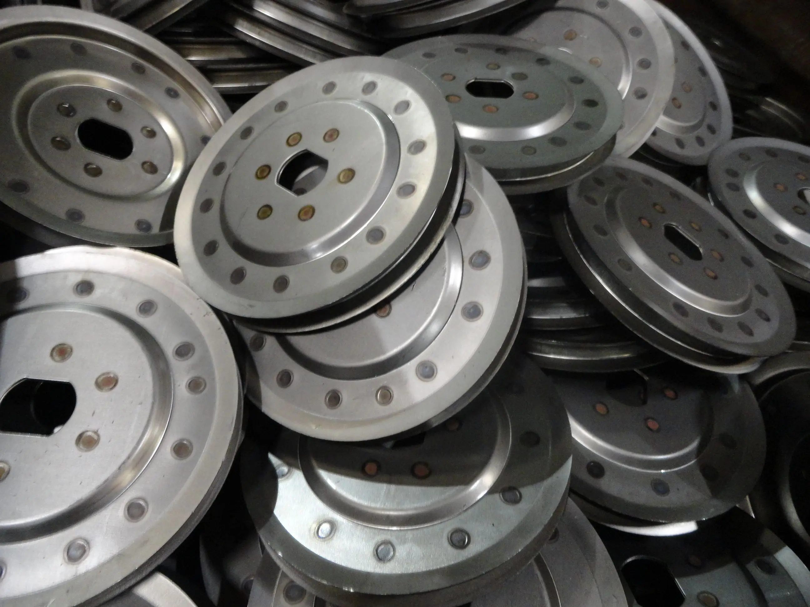 A pile of metal wheels with holes in them.